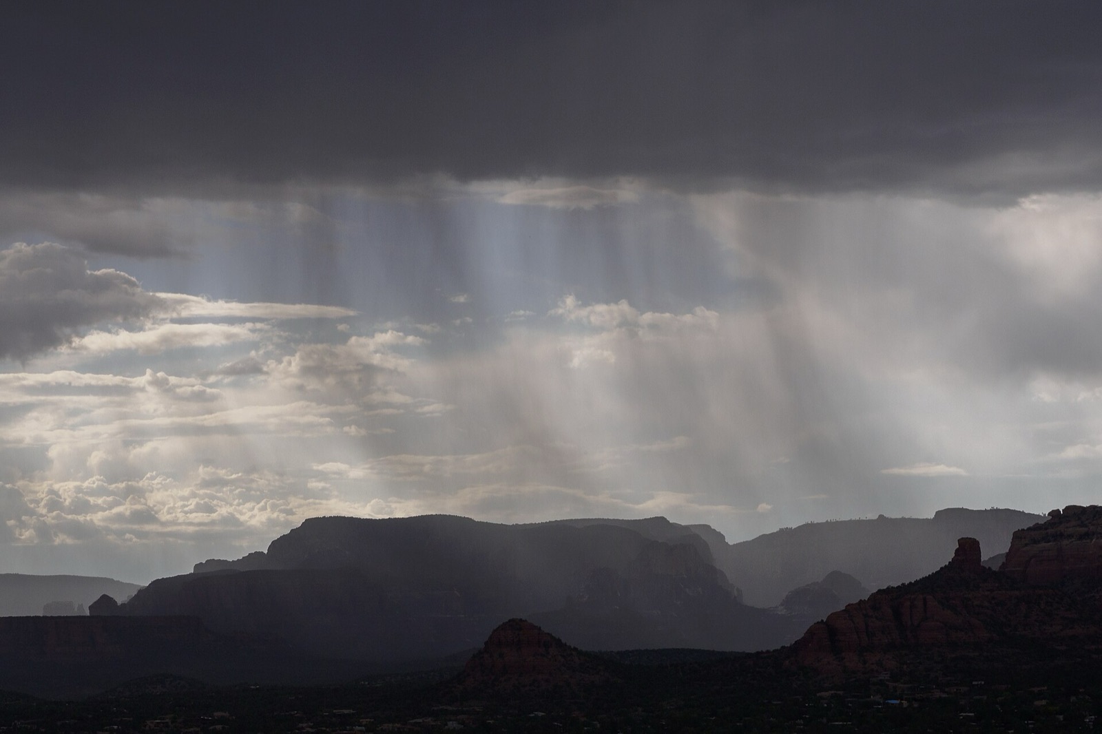 A rain squall with visible curtains of rain sweeping over the red rock formations around Sedona, Arizona